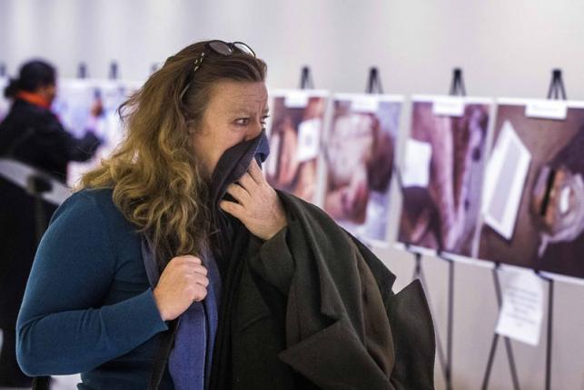 A woman reacts as she looks at a gruesome collection of images of dead bodies taken by a photographer, who has been identified by the code name "Caesar," at the United Nations Headquarters in New York, March 10, 2015. REUTERS/Lucas Jackson